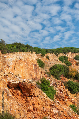Nature background with wall of rock, blue sky and crowns of forest