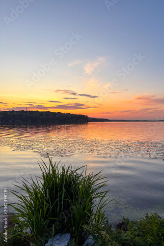A peaceful walk on sunset unfolds along the Ternopil Pond in Ternopil, Ukraine, where calm waters and lush surroundings create a serene urban retreat.
