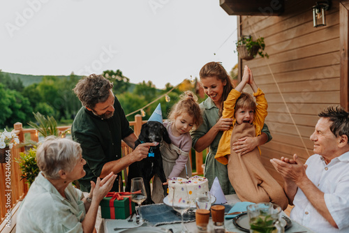 Картината върху платно Multi generation family celebrating birthday and have garden party outside in the backyard on patio
