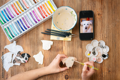 Person painting clay dog face looking at reference
