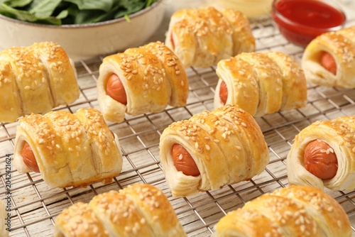 Puff pastry. Tasty sausages in dough and ketchup on white wooden table, closeup