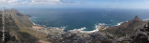 High resolution stitched panorama from Table Mountain, South Africa, featuring a wide angle view of Camps Bay, the Twelve Apostles mountain range, Lion's Head peak, and the vast Atlantic Ocean.