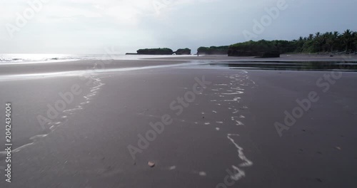 Bali landscape captured by drone shows beach, water, rocks, and trees during cloudy day