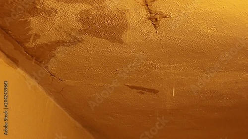 Close-up of textured wall with water stains and cracks, showing signs of damage. Detailed view of a textured wall surface exhibiting water damage, cracks, and discoloration, suggesting structural