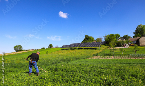 Tableau sur toile A farmer mows grass with a hand scythe, foraging in the countryside