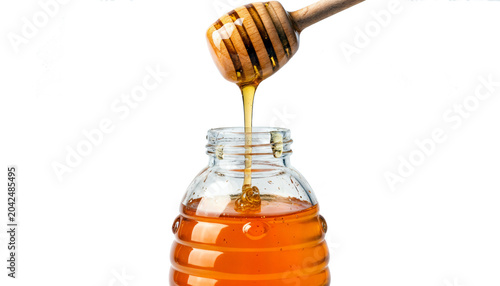 Golden honey dripping into glass jar with dipper