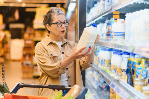Photos Woman choosing milk at supermarket dairy aisle