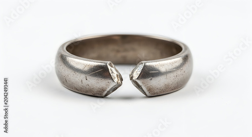 Broken silver metal ring on a white background, concept of divorce or separation.
