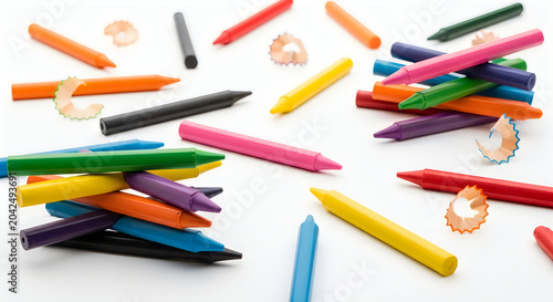 Colorful wax crayons scattered on a white background with pencil shavings, creative art and school supplies concept.