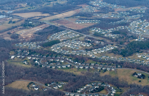Aerial view of suburban residential subdivisions expanding into rural farmland and forest in Northern Virginia, showing active land development and new housing construction in Washington DC exurban