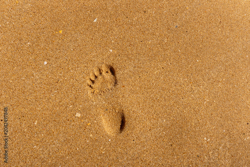 Einzelner Fußabdruck im feinen Sand am Strand bei natürlichem Sonnenlicht und sommerlicher Atmosphäre