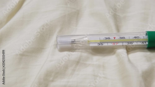 Thermometer indicating normal body temperature on bed