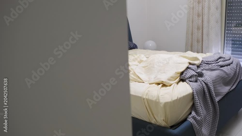 Unmade bed with rumpled sheets and blankets in bedroom