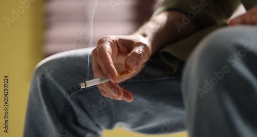 Foto Man smoking cigarette at home, closeup. Bad habit