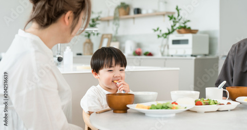 Konstfotografi A boy eating a meal with his parents and family.