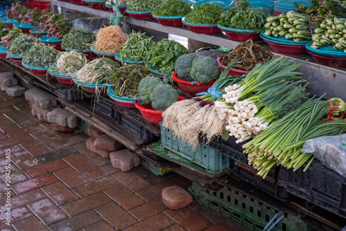 Variety of fresh vegetables and Korean spring herbs displayed in colorful baskets at a traditional outdoor market.