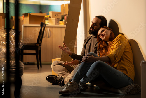 Foto Man and woman thinking about redecoration ideas in their first home, sharing ideas on furniture and decorations arrangement, Proud homeowners evaluating interior design options, happiness