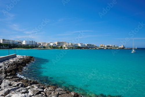 View over seawall  groyne  harbour wall  harbor wall with one yacht on turquoise sea under blue sky