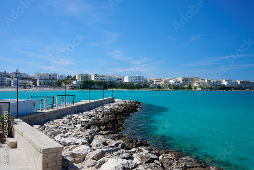 View over seawall  groyne  harbour wall  harbor wall with no boats on turquoise sea under blue sky