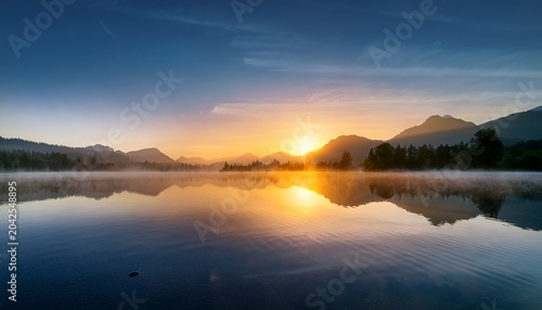 serene sunrise over misty mountains and calm water reflection