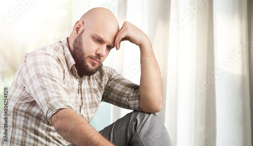 Foto Sad handsome man sitting holding hand over head