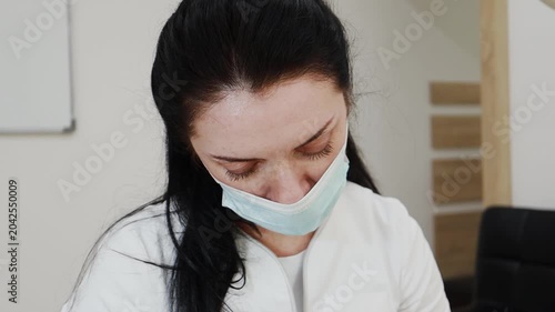 A female professional cosmetologist applies protective ointment to a client after a procedure