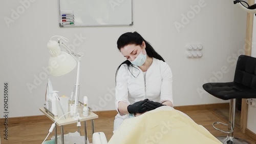 A female professional cosmetologist applies protective ointment to a client after a procedure