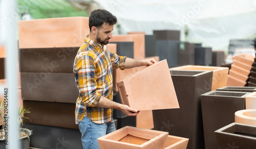 Canvastavla Among large number of goods, man chooses large flower pot-tub