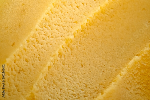 Detailed macro shot of gourmet mango frozen cream showing sculpted diagonal ridges. Macro Texture of ice cream. The warm yellow tones and soft lighting create an indulgent. Artisanal food texture.