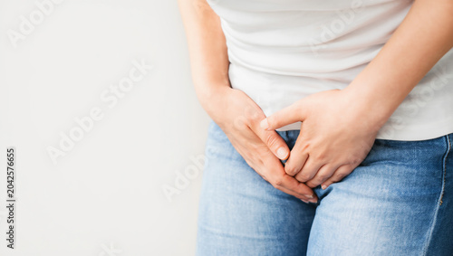 Woman clutches her lower abdomen in discomfort, signaling bladder or pelvic health issues.