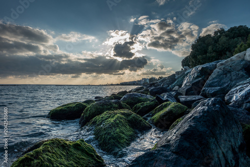 Bild auf Leinwand Dramatic Sunset Over Rocky Black Sea Coastline with Moss-Covered Boulders, Novor