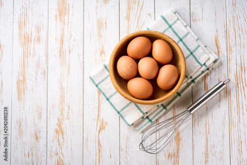 raw organic eggs in a bowl on a white table, top view.