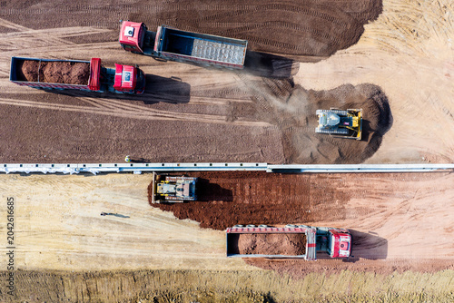 Aerial earthmoving construction site with dump trucks