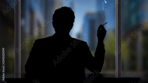 Man silhouette seated at a desk cigarette in hand