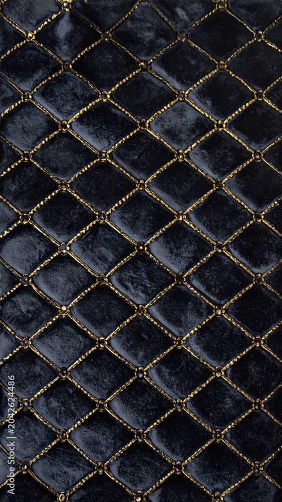 Fototapeta premium Elegant Deep Navy Blue Velvet Fabric Texture Featuring Luxurious Diamond Quilted Stitching with Metallic Gold Threading for Sophisticated Interior Design Projects