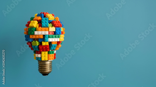 Creative light bulb idea made of colorful building blocks symbolizing innovation and problem-solving on a solid blue background