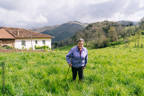 Elderly cheesemaker woman standing in green rural field