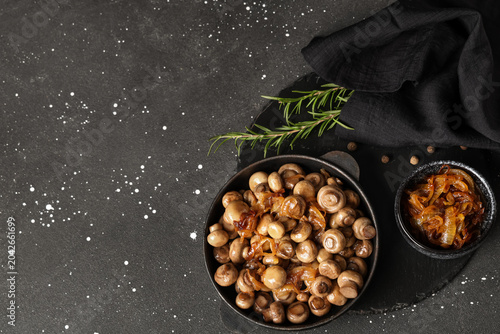 Fotografía Frying pan with roasted mushrooms, rosemary and bowl of onion on black backgroun