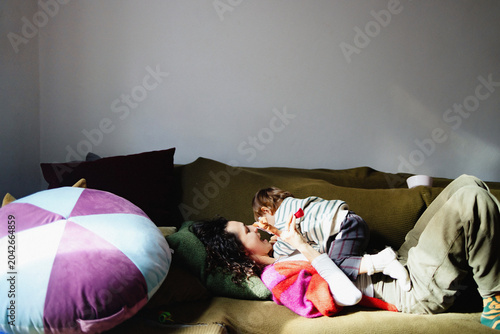Mother and Child Cuddling Playfully on Green Sofa
