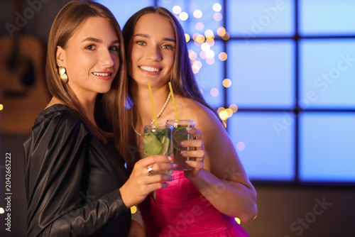 Beautiful young happy women with glasses of mojito in bar