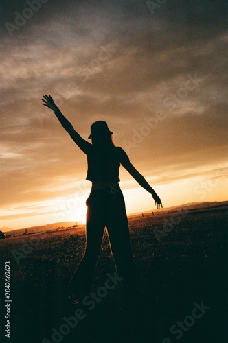 joyous silhouette of woman standing in front of sunset in field film