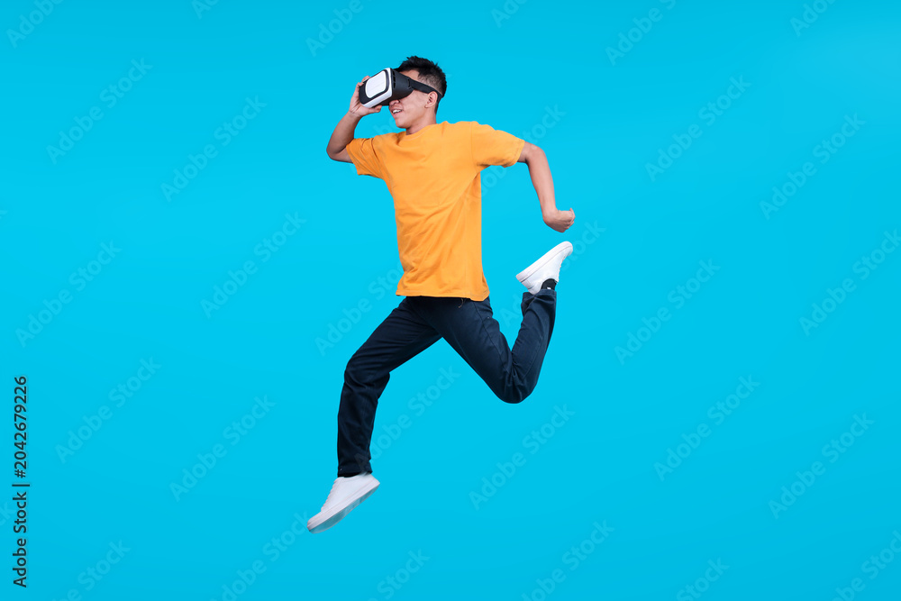 Fototapeta premium Full Length of Energetic Young Man Jumping High Wearing VR Headset
