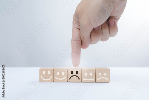 Foto Customer feedback concept with wooden emotion blocks and a hand selecting a negative rating, representing customer dissatisfaction, service quality issues, complaint management, user experience