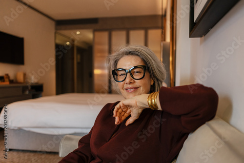 Smiling senior woman relaxing inside luxurious hotel room