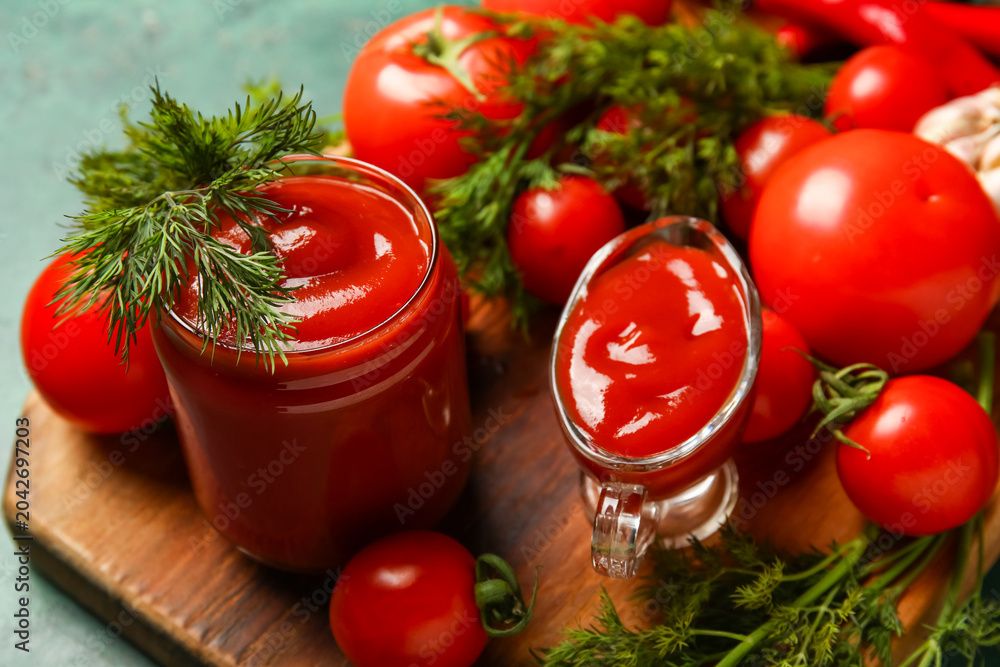Obraz premium Jar and gravy boat with tasty ketchup and fresh vegetables on table, closeup