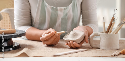 Fotografía Female sculptor with tool carving clay figure in workshop