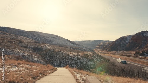 Highway traffic passing through a snowy mountain valley landscape