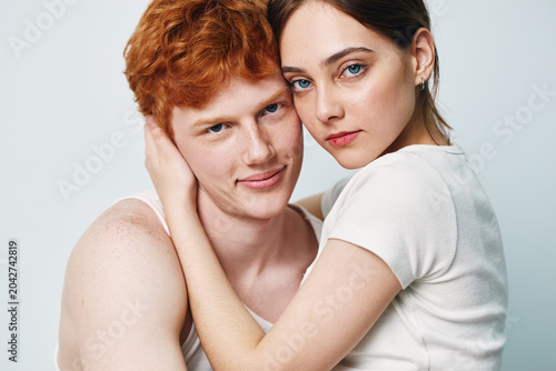 Obraz na plátně Couple, young man and woman in close embrace with affectionate expression on white background