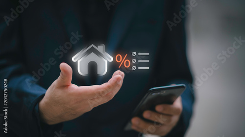 Fotografie Businessman using telephone and laptop with house interest rate icon