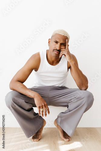 Man with mustache squatting on floor